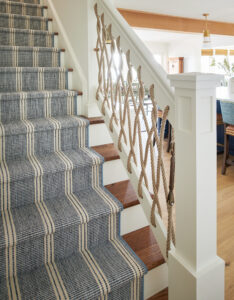 nautical staircase with blue striped runner and rope banisters by MuellerHomes.com